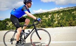 Ciclista pedalando ao ar livre, em uma rua asfaltada